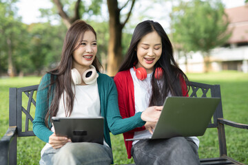 Fototapeta premium Smiling young Asian student wearing headphones talking in online chat using laptop.