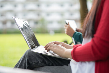 Smiling young Asian student wearing headphones talking in online chat using laptop.