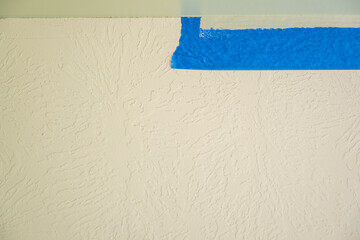 Freshly painted wall corner with blue tape applied for a clean finish in a home renovation project