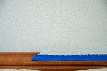Renovation project underway with painter's tape on wooden trim and freshly prepared wall for...
