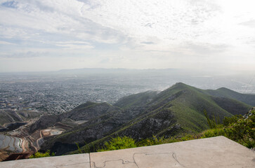 Breathtaking panoramic view of sprawling city nestled among rolling green mountains under cloudy sky