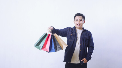 Portrait of handsome Asian man holding shopping bags isolated on white background