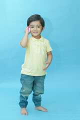 Indian child boy playing with toy mobile phone isolated against blue background. 2-3 year playful kid wear trendy blue jeans and t-shirt having fun. Childhood. Fashion. Copy space