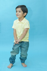 Indian child boy wear trendy blue jeans and t-shirt standing isolated against blue background. 2-3 year playful kid having fun. Childhood. Fashion. Copy space