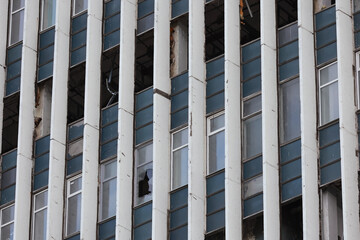Facade Of A Ruined Industrial Or Office Building With Rows Of Broken And Empty Windows. Urban Decay...