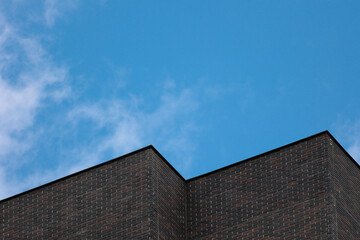 Minimalist Architecture Of A Modern Dark Brick Building Corner Against A Blue Sky With Light...