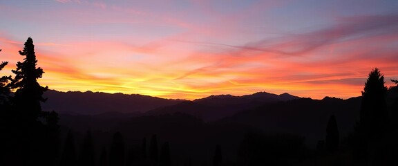 Serene sunrise silhouettes of majestic mountains and dark cypress trees against a vibrant sky,  panoramic,  peaceful