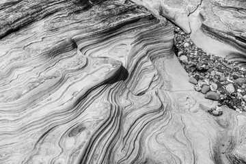 Eroded sandstone layers and pebbles in coastal rock channel