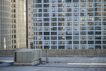 City skyline view with modern buildings and rooftop air conditioning unit at sunset