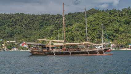 An old sailing ship is anchored in the bay. High masts, ship rigging, rope ladders, lifebuoys,...