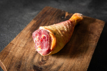 Close-up footage of a raw chicken leg placed on a rotating wooden surface. High-resolution detail...