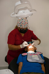 Dentist examining boys teeth in dental clinic