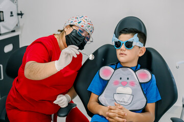 Dentist showing dental mirror to young boy in clinic