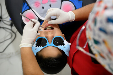 Pediatric dentist examining teeth of young boy wearing funny glasses