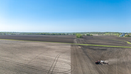 Drone aerial view above a tracter pulling a planter in a ag field. 