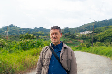 Man standing on rural path surrounded by lush landscape and communications tower in Colombian...
