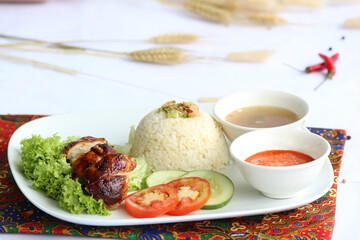 Roasted chicken rice, Southeast Asian dish featuring roasted served with fragrant rice cooked in chicken broth and flavored with aromatics like ginger and garlic accompanied by chili sauce and soup.