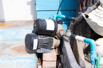 Old water pump motor small attached to concrete floor and structure with plastic pipe for water circulation. Industrial water technology. Important devices in water supply system.