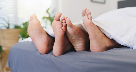 Sleeping, couple and feet on bed, home or comfortable in bedroom, relationship or together on...