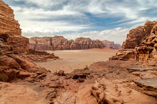 Scenic landscape of Wadi Rum desert in Jordan, captured under soft daylight with dramatic rock formations and wide sandy plains stretching into the horizon.