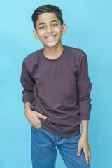 Young indian boy wearing casual full sleeves T-shirt and jeans.posing against blue background.Studio shot. Kid trendy outfit.