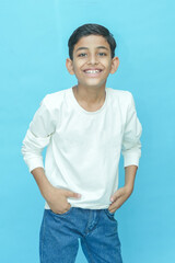 Young indian boy wearing casual white T-shirt and jeans.posing against blue background.Studio shot. Kid trendy outfit.