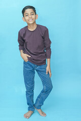 Young indian boy wearing casual full sleeves T-shirt and jeans.posing against blue background.Studio shot. Kid trendy outfit.