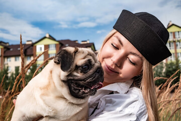 Young happy beautiful woman holding and hugging her beloved dog during a walk with harness and...