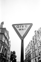 Give way sign dominating london street in monochrome film photography