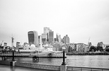 Hms belfast moored on the river thames with city of london skyline in grainy black and white