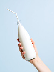 Hand holding a bottle of milk with straw on light pastel solid background, super realistic cinematic style with dramatic lighting and neutral colors, healthy drink concept.