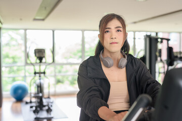 Fototapeta premium Asian non binary transgender woman in gym training for healthy fitness lifestyle with exercise bike