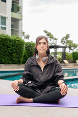 Non binary Asian transgender woman doing yoga session by the swimming pool