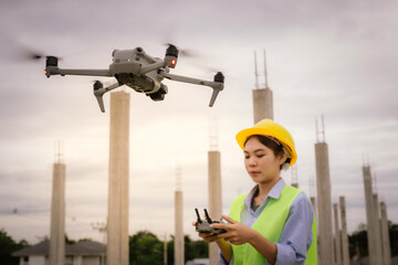 A female construction worker in a safety vest and hard hat operates a drone on-site, using smart technology for surveying, inspection, and monitoring in modern engineering projects.