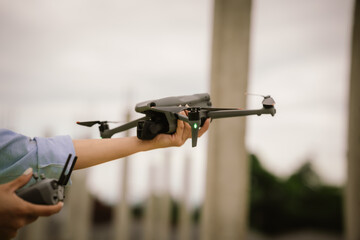 A woman operates a drone using a handheld remote control outdoors, showcasing modern technology,...