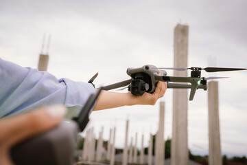 A woman operates a drone using a handheld remote control outdoors, showcasing modern technology,...
