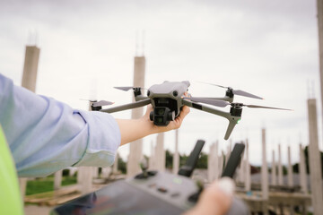 A woman operates a drone using a handheld remote control outdoors, showcasing modern technology,...