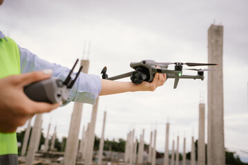 A woman operates a drone using a handheld remote control outdoors, showcasing modern technology,...