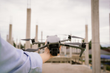 A woman operates a drone using a handheld remote control outdoors, showcasing modern technology,...