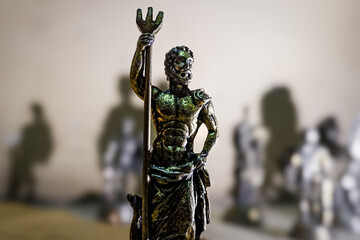 Miniature metal statues with dramatic shadows on textured wall