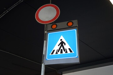 Illuminated pedestrian crossing sign at Fiumicino Airport (Rome, Italy). Mounted on a metal pole...