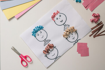 Children’s paper craft project with cartoon faces and colorful textured paper hair. Fun and...