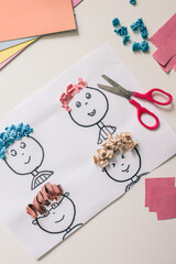 Children’s paper craft project with cartoon faces and colorful textured paper hair. Fun and...
