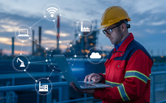 Engineer uses laptop for industrial IoT network analysis at plant