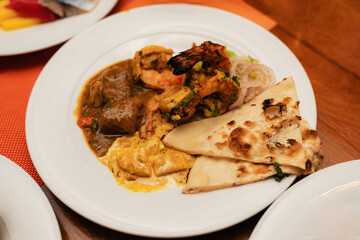 Indian Cuisine Buffet Plate with Grilled Prawns, Curry, Paneer and Naan