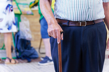 unrecognizable Senior man gripping a cane for support, highlighting themes of aging, mobility, and...