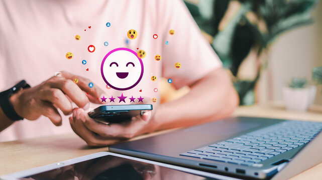 Customer using smartphone with happy emoji, five-star rating, and social media reaction icons. Concept of customer feedback, online review, and digital user engagement.