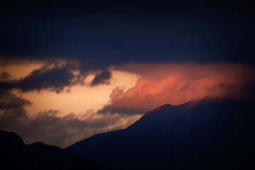 dark red clouds and a lighting sky at a summer evening on the mountains