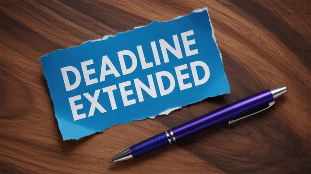 Deadline Extended Notice Written on Torn Blue Paper with a Pen on Wooden Background