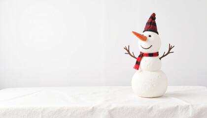Snowman wearing a red and black hat and scarf with a happy face on a white background and copy space